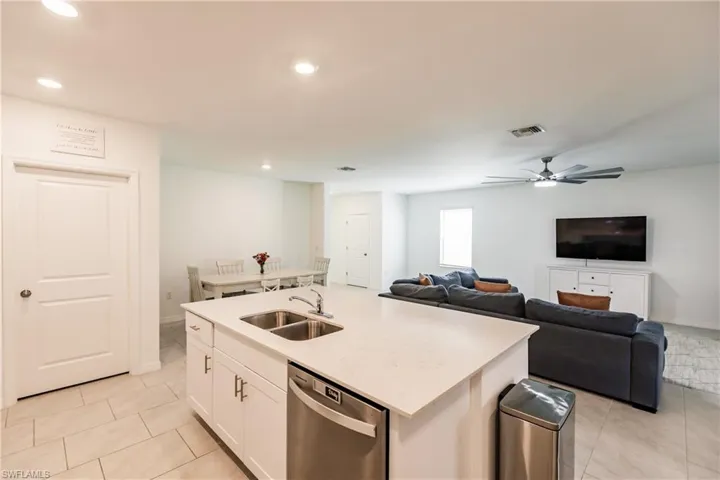 Kitchen featuring white cabinets, sink, ceiling fan, a center island with sink, and stainless steel dishwasher
