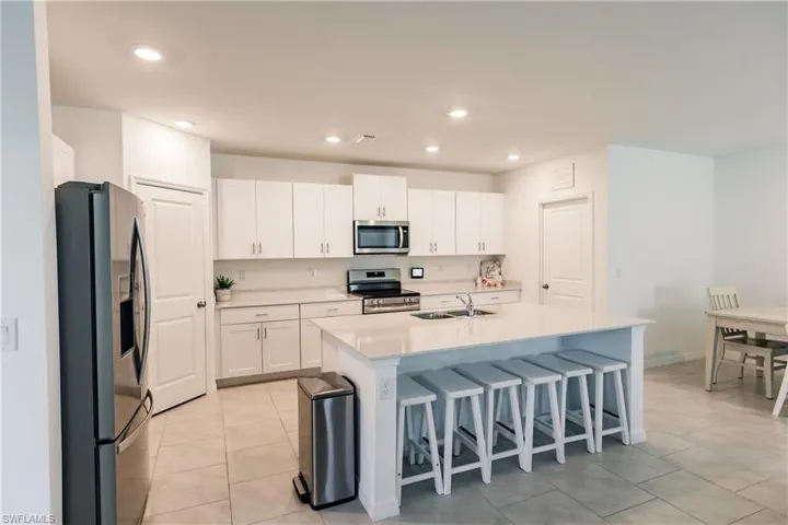 Kitchen featuring a breakfast bar area, appliances with stainless steel finishes, an island with sink, sink, and white cabinets
