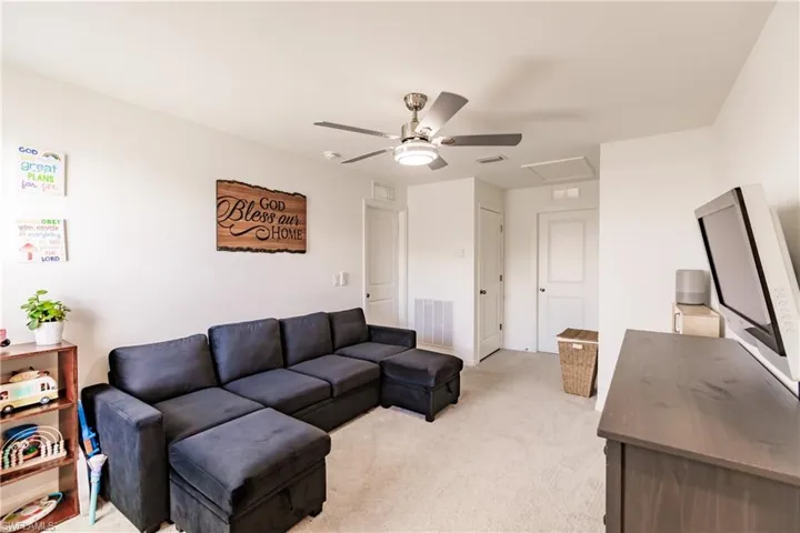Carpeted living room with ceiling fan