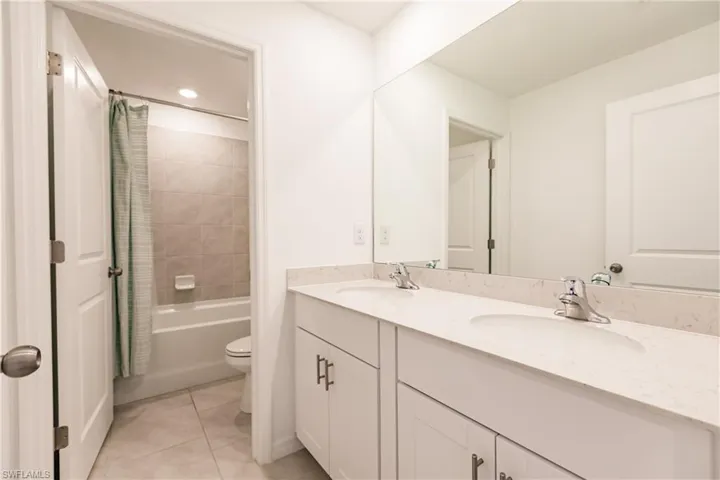 Full bathroom featuring tile patterned flooring, vanity, toilet, and shower / bath combo with shower curtain