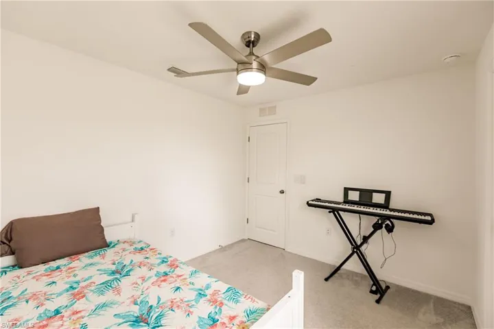 Carpeted bedroom featuring ceiling fan