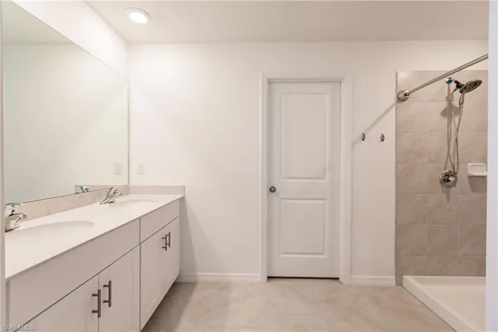 Bathroom with tiled shower, vanity, and tile patterned floors
