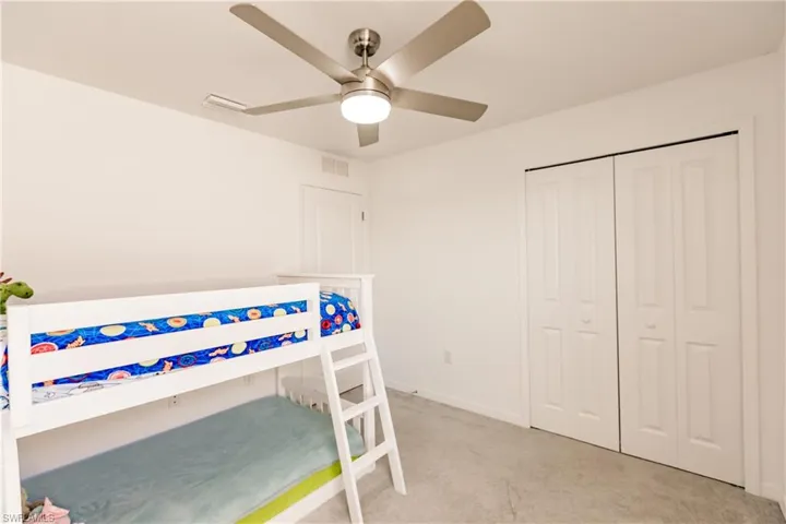Bedroom with a closet, ceiling fan, and light colored carpet