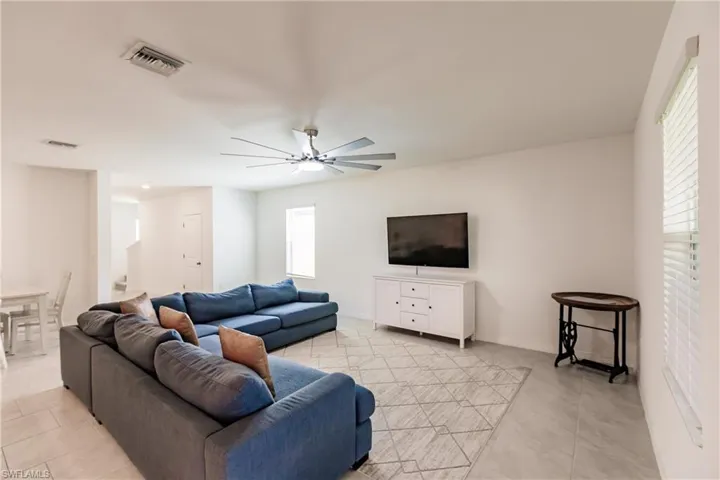 Living room with a healthy amount of sunlight, light tile patterned floors, and ceiling fan