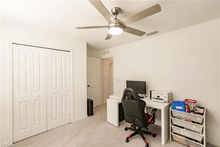 Home office with ceiling fan and light colored carpet