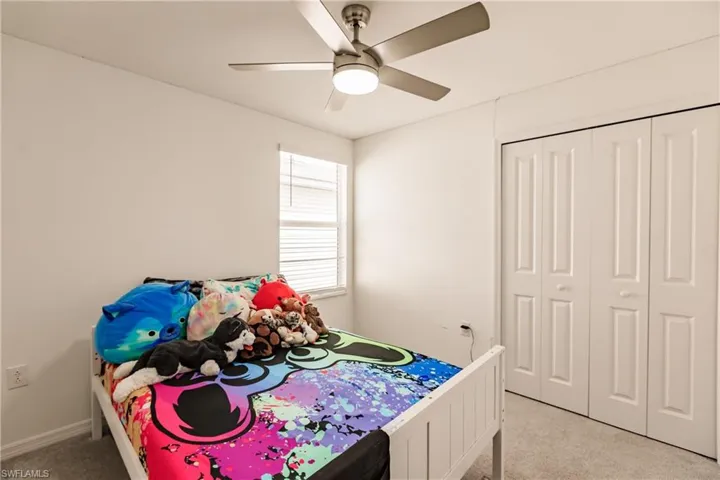 Bedroom featuring ceiling fan, a closet, and light carpet