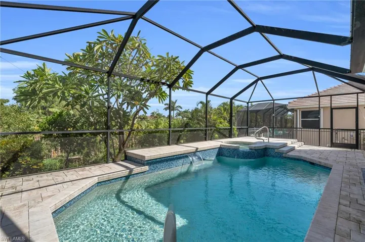 View of swimming pool with glass enclosure, a pool with connected hot tub, and a patio