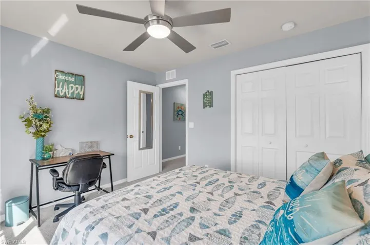 Carpeted bedroom with baseboards, a ceiling fan, visible vents, and a closet