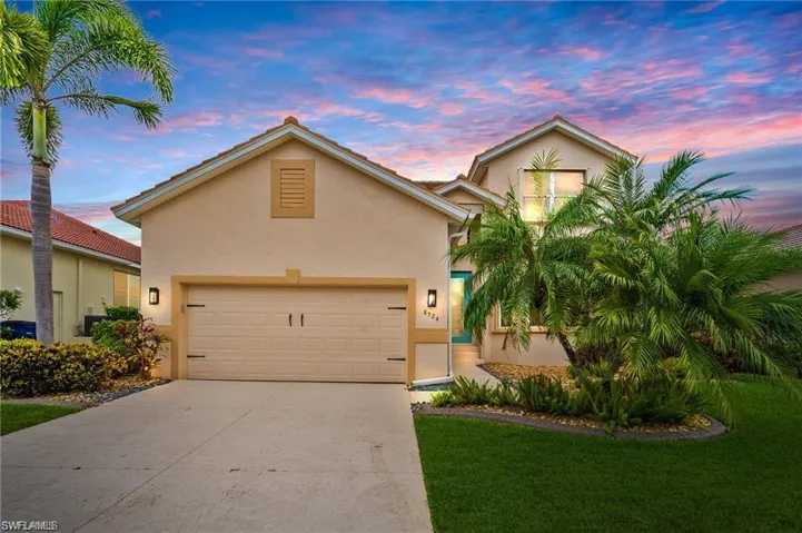 View of front of home with a garage, driveway, a front yard, and stucco siding