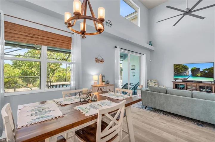 Dining area with ceiling fan with notable chandelier, light wood-style flooring, and a towering ceiling