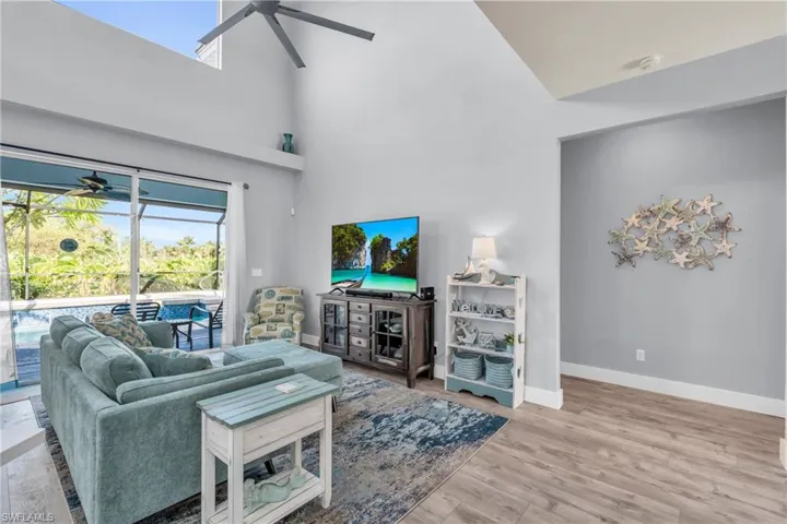 Living area with wood finished floors, baseboards, high vaulted ceiling, and ceiling fan