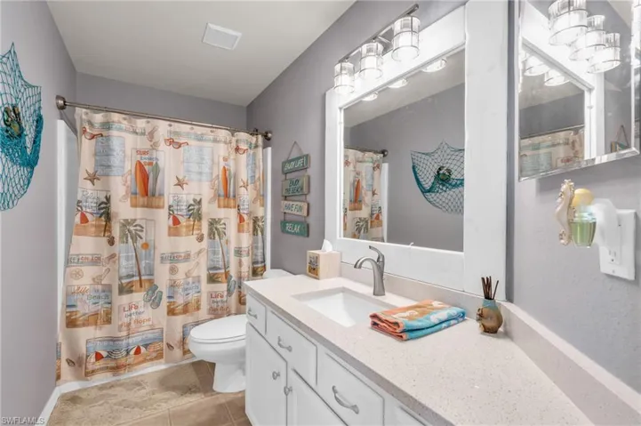 Full bathroom featuring toilet, visible vents, tile patterned flooring, a shower with shower curtain, and vanity