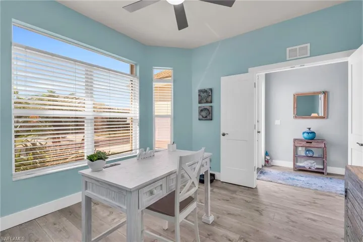 Home office with light wood-style flooring, visible vents, baseboards, and ceiling fan
