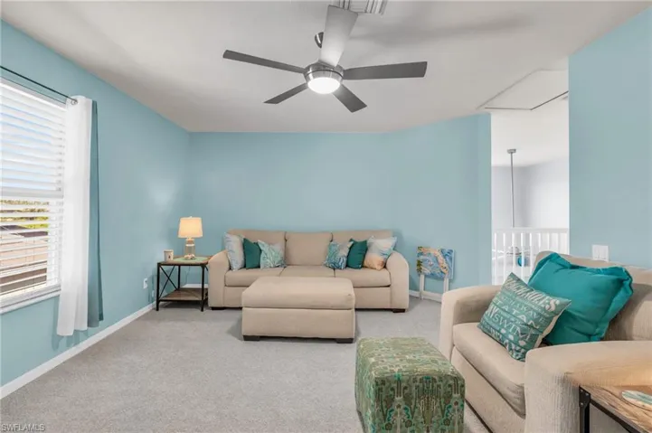 Living room with carpet floors, baseboards, and ceiling fan