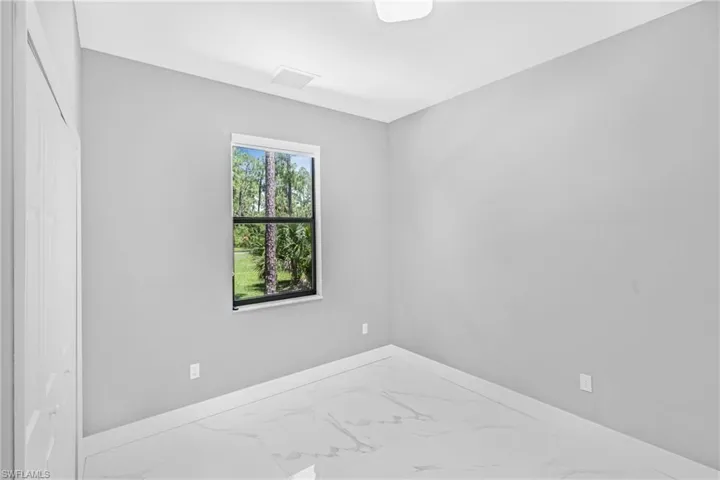 Empty room featuring marble look tiles and baseboards
