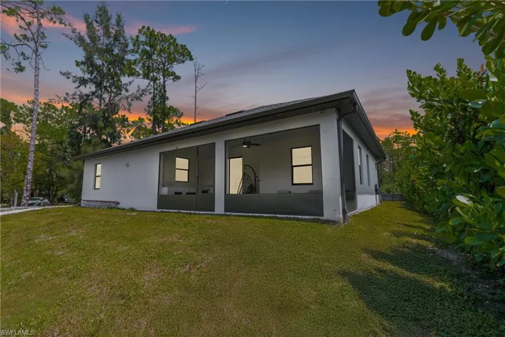 Back of property featuring stucco siding, a lawn, and a ceiling fan