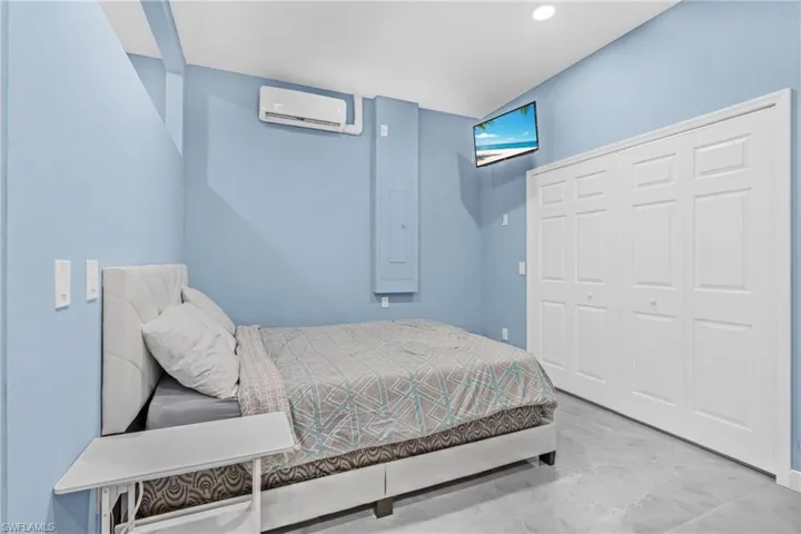 Bedroom with a wall mounted AC and a closet