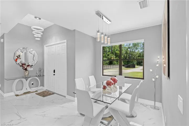 Dining room with a chandelier and marble look tiles