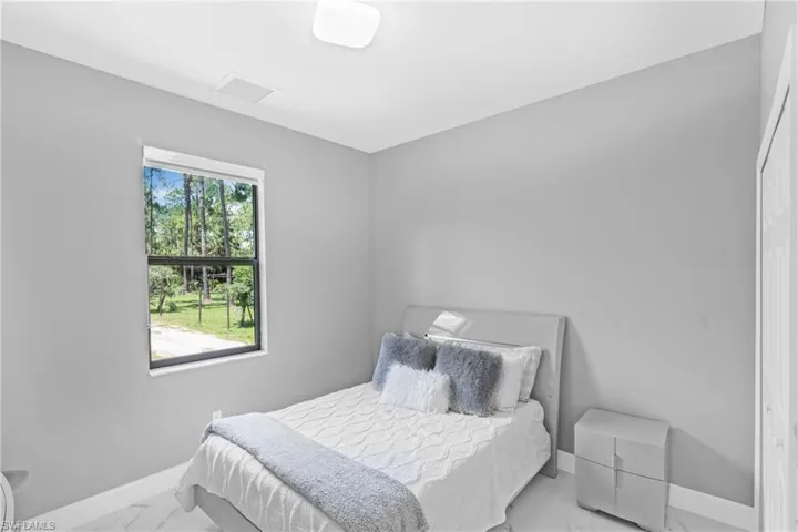 Bedroom with marble finish floors and a closet