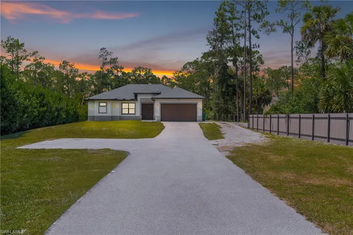 View of front facade with a garage, stucco siding, and driveway