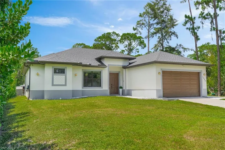View of front facade with a garage, stucco siding, concrete driveway, and a front lawn