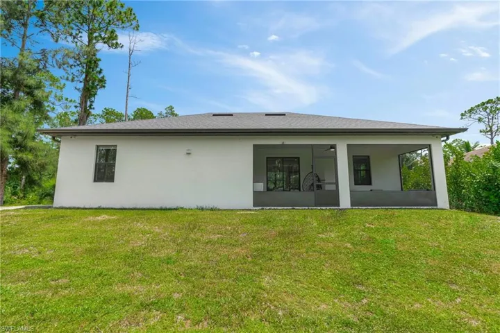 Back of property with a yard, stucco siding, and ceiling fan