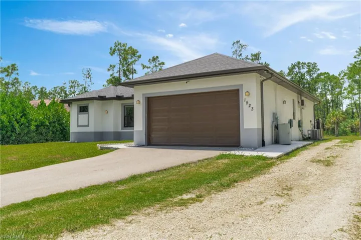 View of front of property with stucco siding, driveway, an attached garage, and a shingled roof