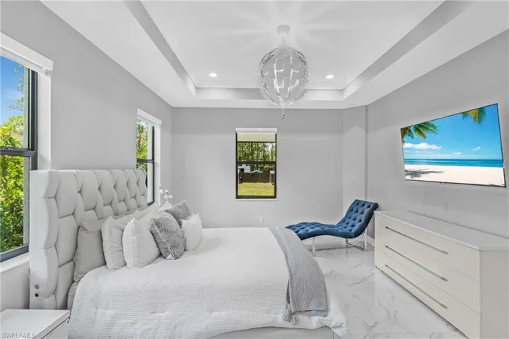 Bedroom featuring marble look tiles, recessed lighting, a raised ceiling, and crown molding