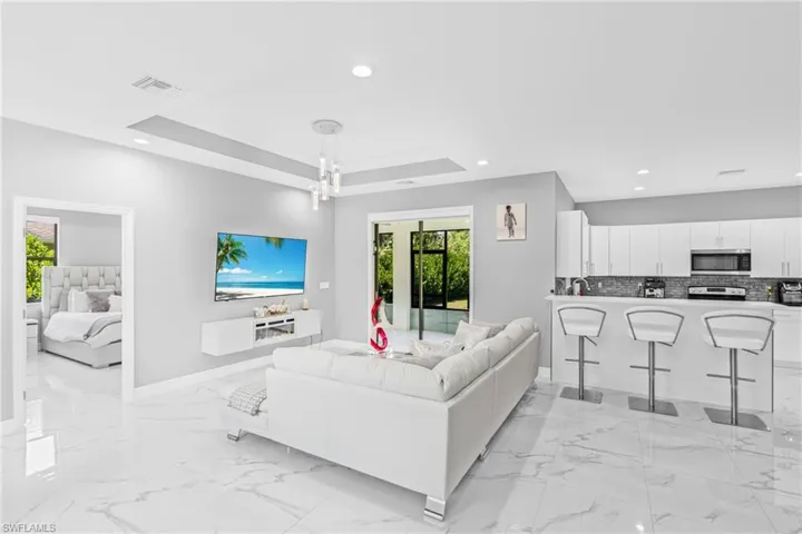 Living room with light marble finish floors, recessed lighting, and a tray ceiling
