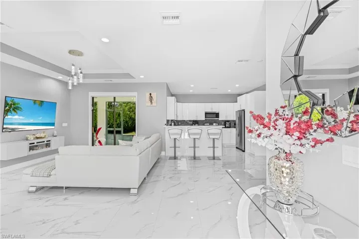 Living room featuring light marble finish floors, a tray ceiling, and recessed lighting