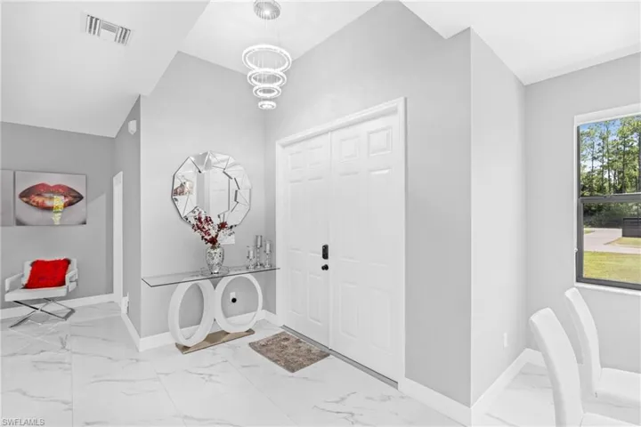Entrance foyer featuring light marble finish flooring and a chandelier