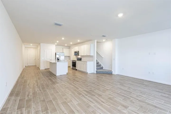 Kitchen featuring open floor plan, a center island with sink, white cabinetry, appliances with stainless steel finishes, and recessed lighting