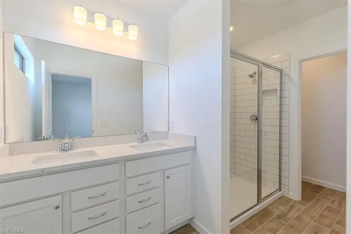 Full bathroom with double vanity, a stall shower, and wood tiled floors