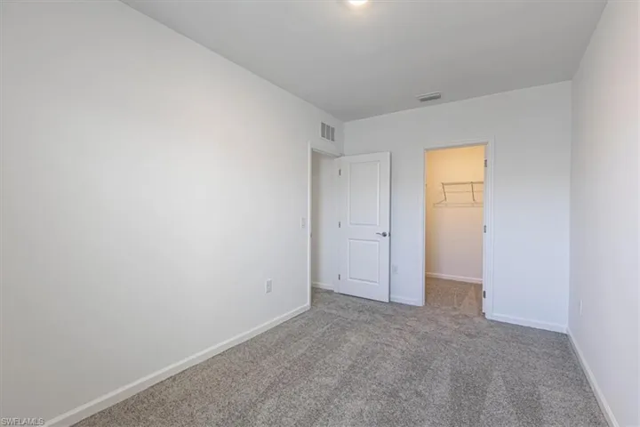 Unfurnished bedroom featuring a walk in closet and carpet