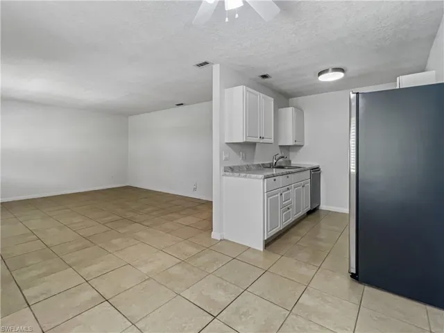 Kitchen featuring stainless steel appliances, ceiling fan, white cabinets, a textured ceiling, and light tile patterned floors