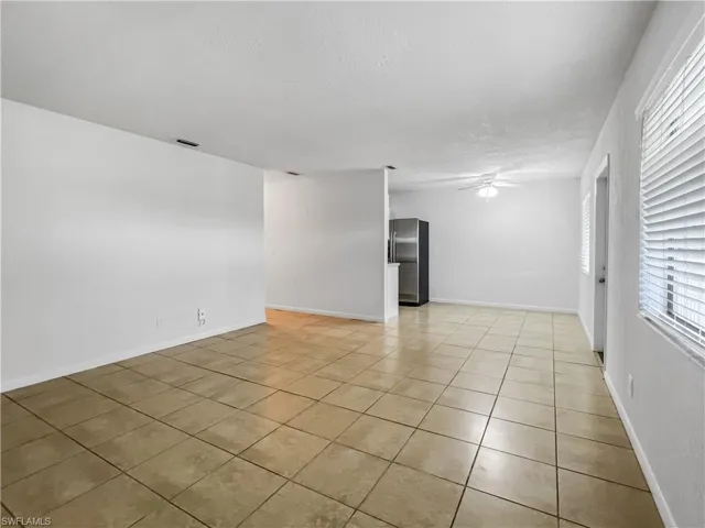 Spare room with light tile patterned flooring, a ceiling fan, plenty of natural light, and a textured ceiling