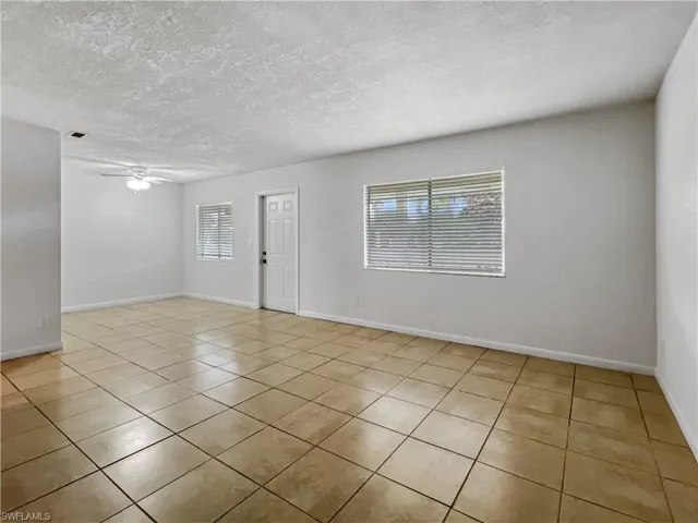 Unfurnished room with light tile patterned flooring, a ceiling fan, and a textured ceiling