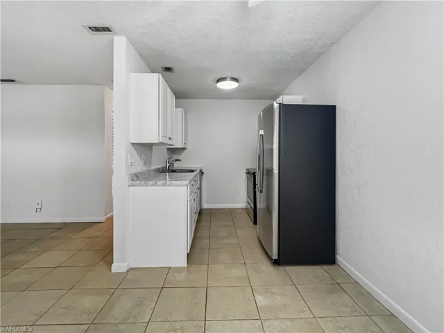 Kitchen featuring appliances with stainless steel finishes, light countertops, white cabinets, a textured ceiling, and light tile patterned floors