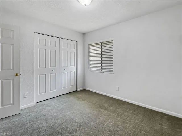 Unfurnished bedroom with carpet, a textured ceiling, and a closet