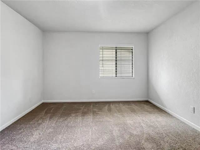 Spare room featuring carpet floors, a textured ceiling, and a textured wall