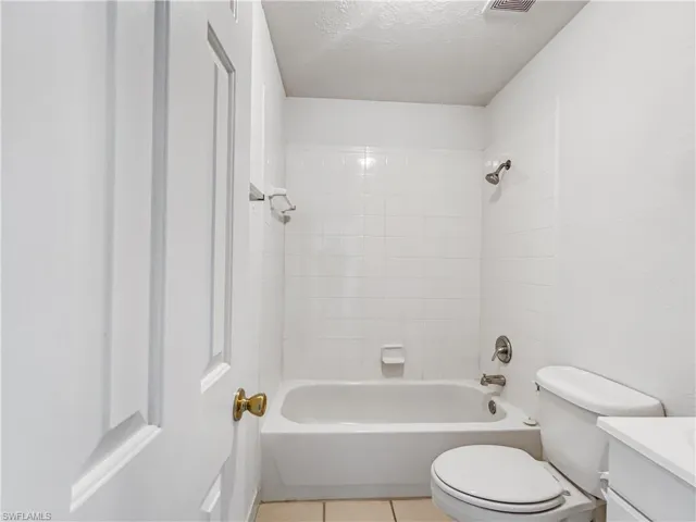 Bathroom featuring vanity, a textured ceiling, bathing tub / shower combination, and tile patterned flooring