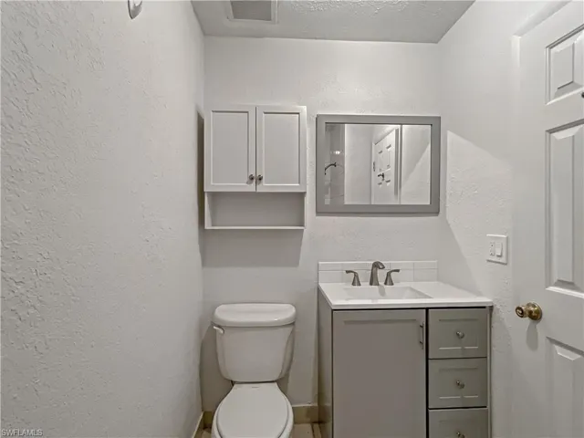 Half bath with vanity and a textured wall