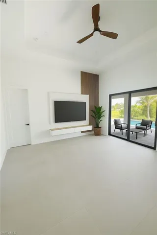Unfurnished living room featuring a raised ceiling and ceiling fan