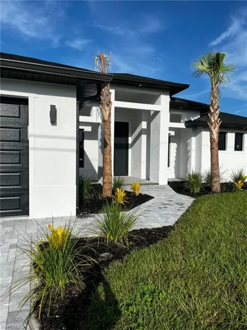 View of exterior entry with stucco siding and a lawn
