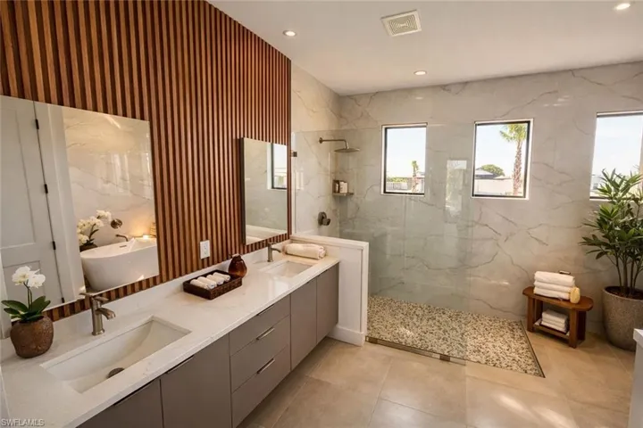 Full bathroom featuring double vanity, a marble finish shower, and recessed lighting