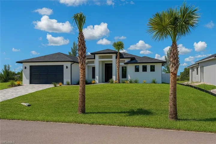 Prairie-style home featuring stucco siding, a front lawn, decorative driveway, and an attached garage