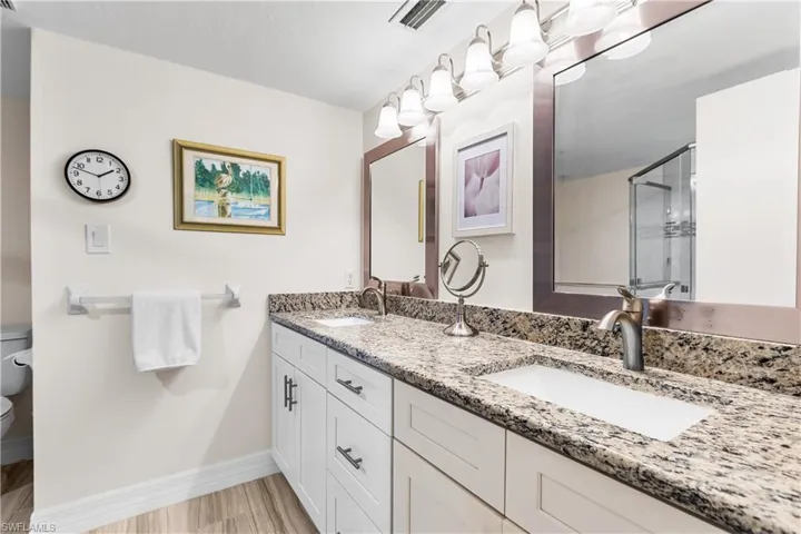 Bathroom with toilet and dual bowl vanity