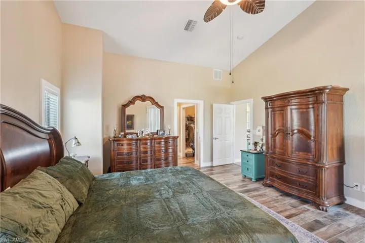 Bedroom featuring high vaulted ceiling, wood finished floors, a ceiling fan, and a walk in closet