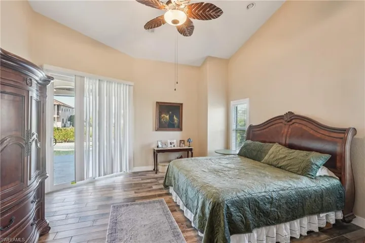 Bedroom featuring access to exterior, wood finished floors, a ceiling fan, and high vaulted ceiling