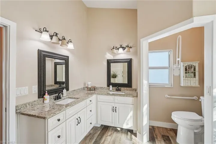 Full bathroom featuring double vanity and wood finished floors